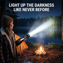 Woman camping beside a lake and campfire at night aiming the Titanium Laser Pro flashlight beam across the water