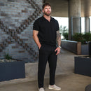 Man wearing black Casual Chinos V2 with a black polo shirt