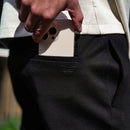 Hand inserting a phone into the side pocket of black chinos