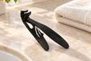 Black angled nail clipper resting on a bathroom counter beside a folded towel.