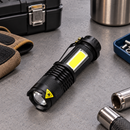 Mini Titanium Laser flashlight on a desk with front light switched on