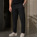 Man wearing black chinos with white shoes against a stone background