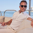Man wearing a white polo shirt while seated on a boat