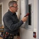 Electrician using NOYAFA NF-824 receiver to scan circuit breakers at an electrical panel with transmitter plugged into wall outlet
