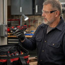 Technician holding NOYAFA NF-824 receiver near an industrial electrical outlet for non-contact voltage detection in a workshop