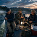 Three men on a fishing boat at dusk using the Titanium Laser Pro Flashlight as a handheld beam and COB lantern on a mountain lake